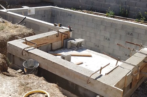 Construction d’une piscine en béton armé dans un jardin paysagé avec coffrage et ferraillage en cours